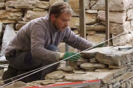Élève construisant un mur en pierre sèche © Artisans bâtisseurs en pierres sèches 